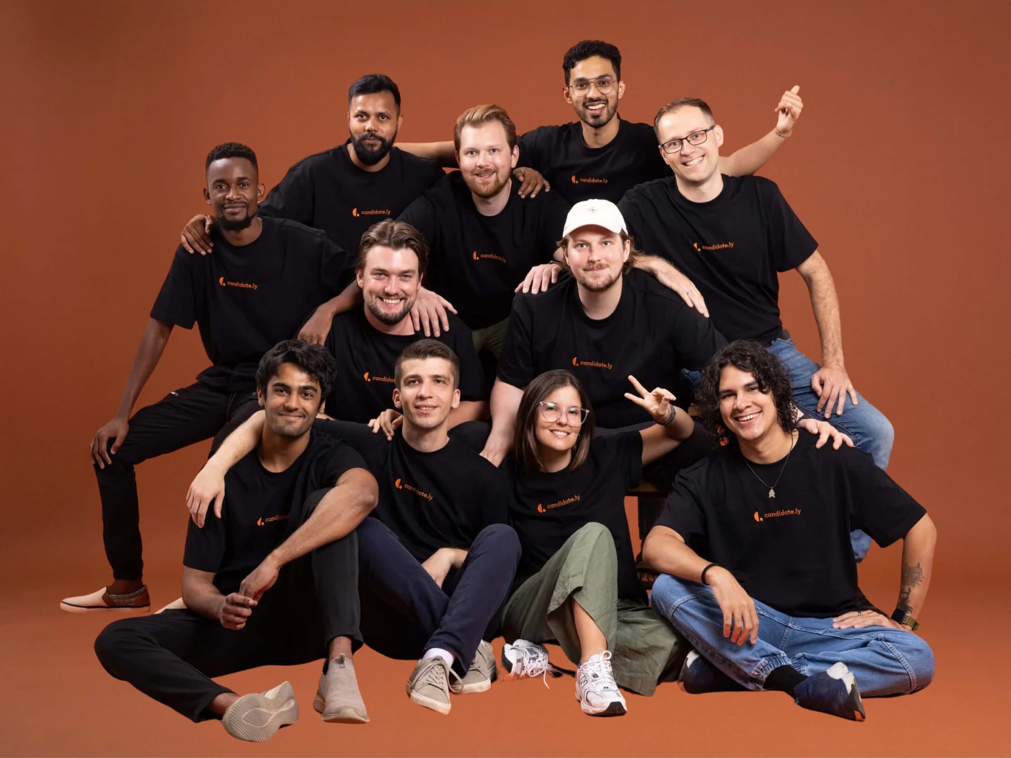 Candidately team wearing branded t-shirts, group photo on orange background